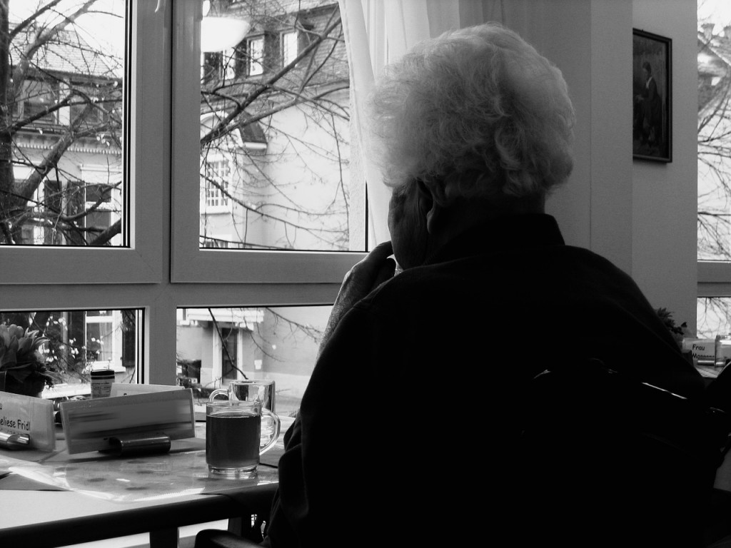 Lonely older woman looking out a window